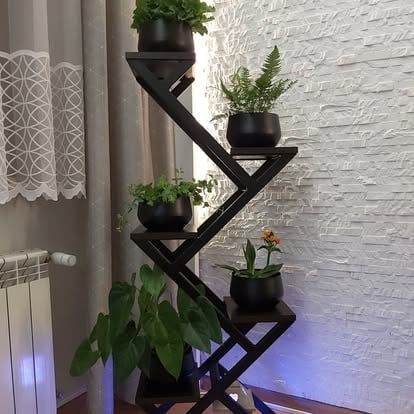 Nowoczesny czarny geometryczny kwietnik z czterema poziomami z doniczkami na białej ścianie z cegły
